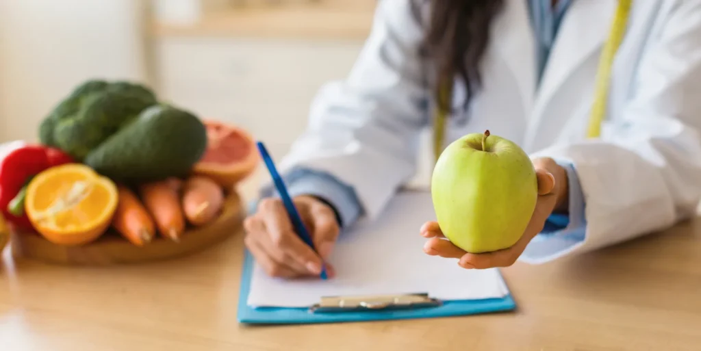 Nutricionista haciendo plan de nutrición personalizado con una manzana en la mano