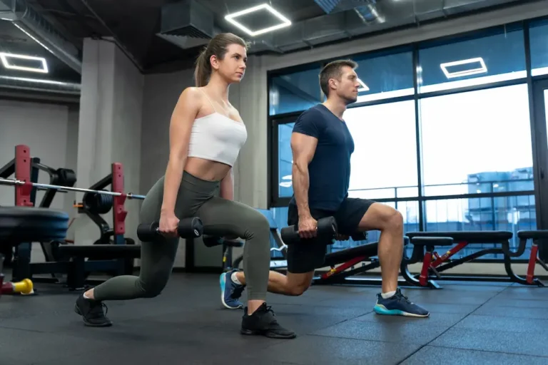 Entrenamiento funcional de dos personas haciendo zancadillas en un gimnasio